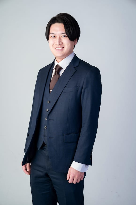 淡い背景でスリーピーススーツの立ち姿ポートレート、役員紹介に使えるプロフィール写真