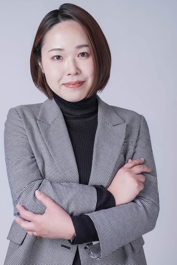 グレー背景でチェック柄ジャケットの上半身ポートレート、会社HP掲載向けのプロフィール写真