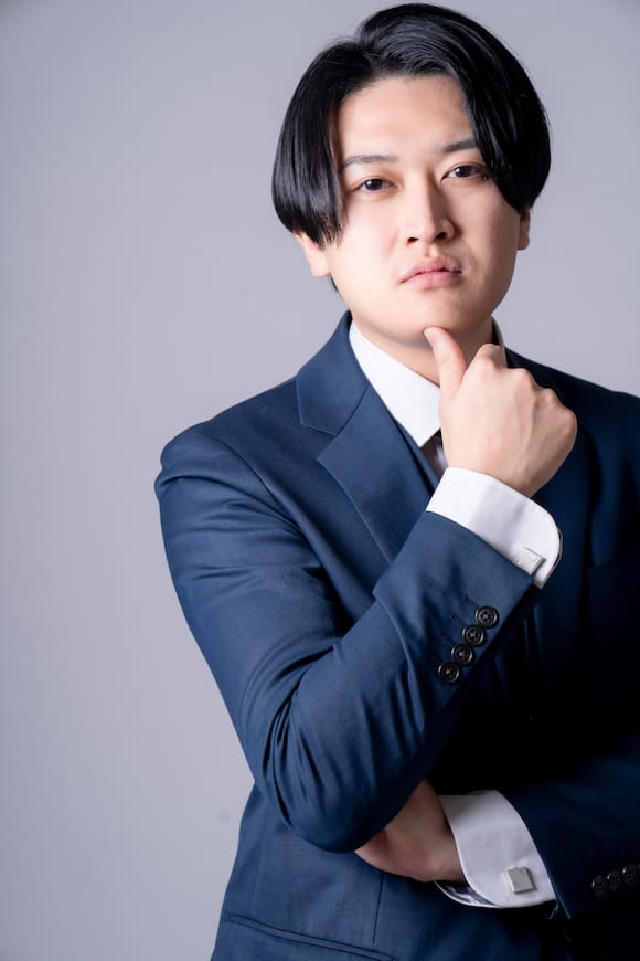 グレー背景でネイビースーツの上半身ポートレート、クリエイティブ職の宣材写真